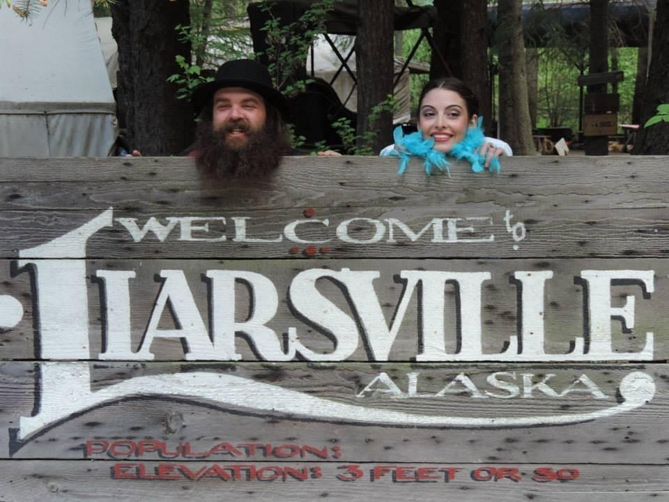 Costumed hosts beside the Liarsville welcome sign in Skagway