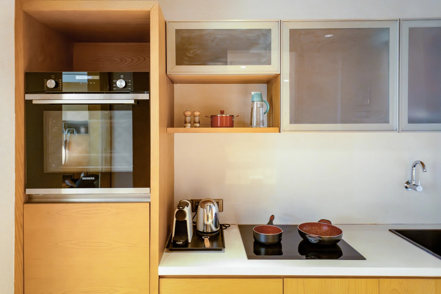 Hotel kitchenette with a cooktop, oven, sink and cookware