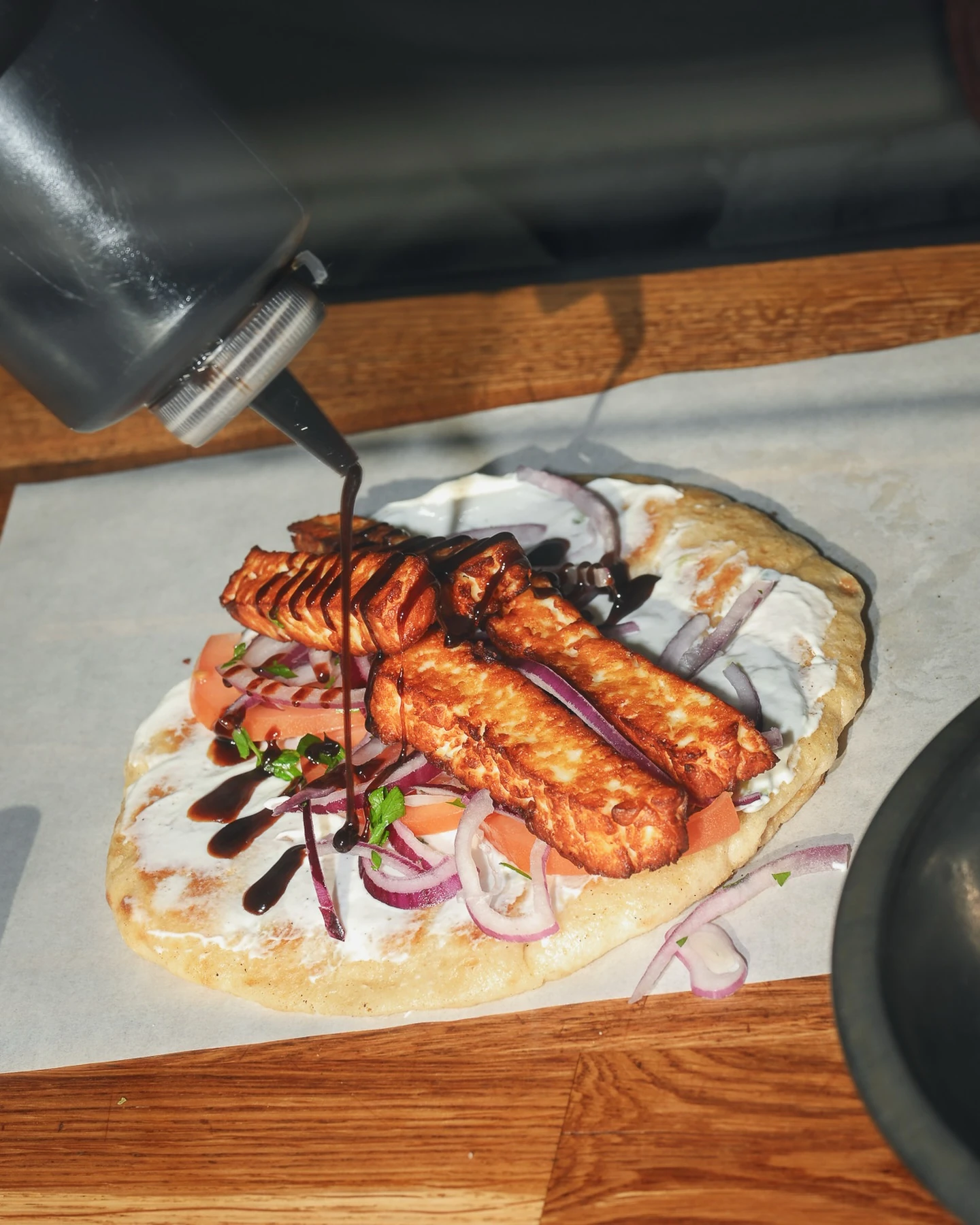 Browned halloumi on pita with tomato, onion, and sauce