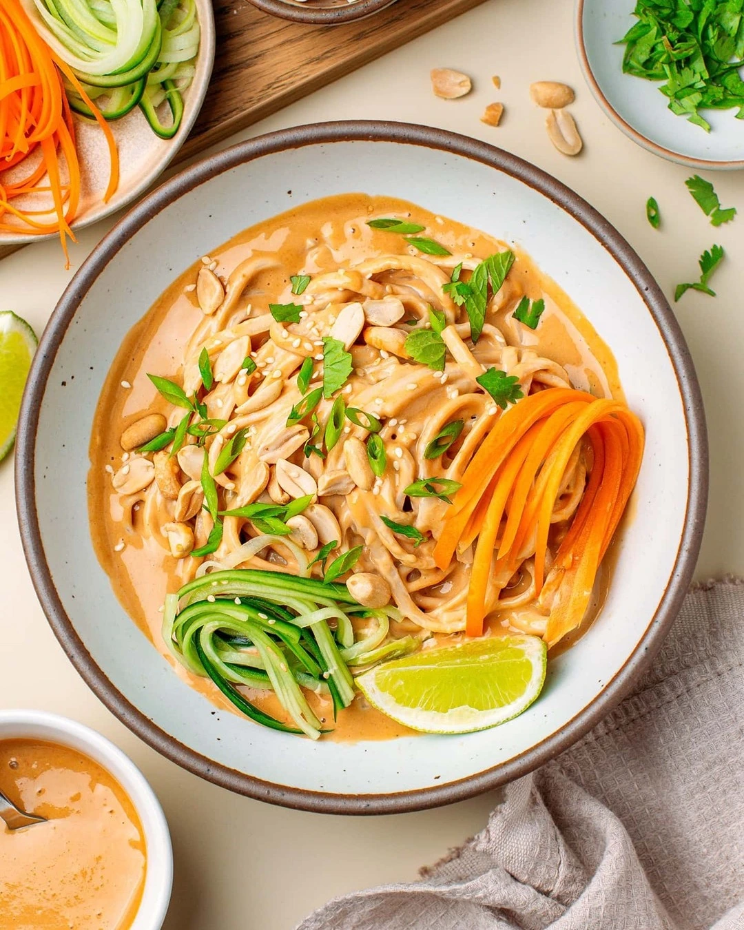 Peanut noodles with crunchy vegetables and a lime wedge