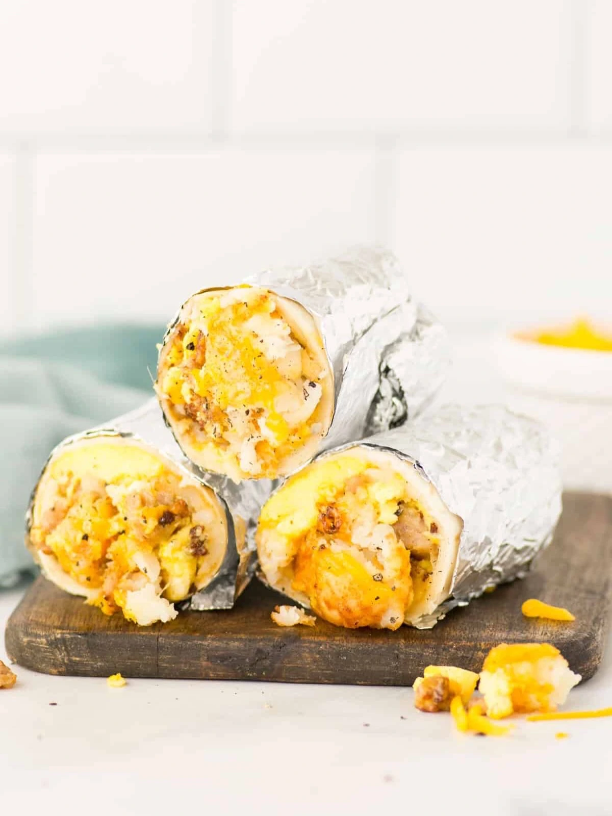 Foil-wrapped breakfast burritos cut open to show the egg and potato filling