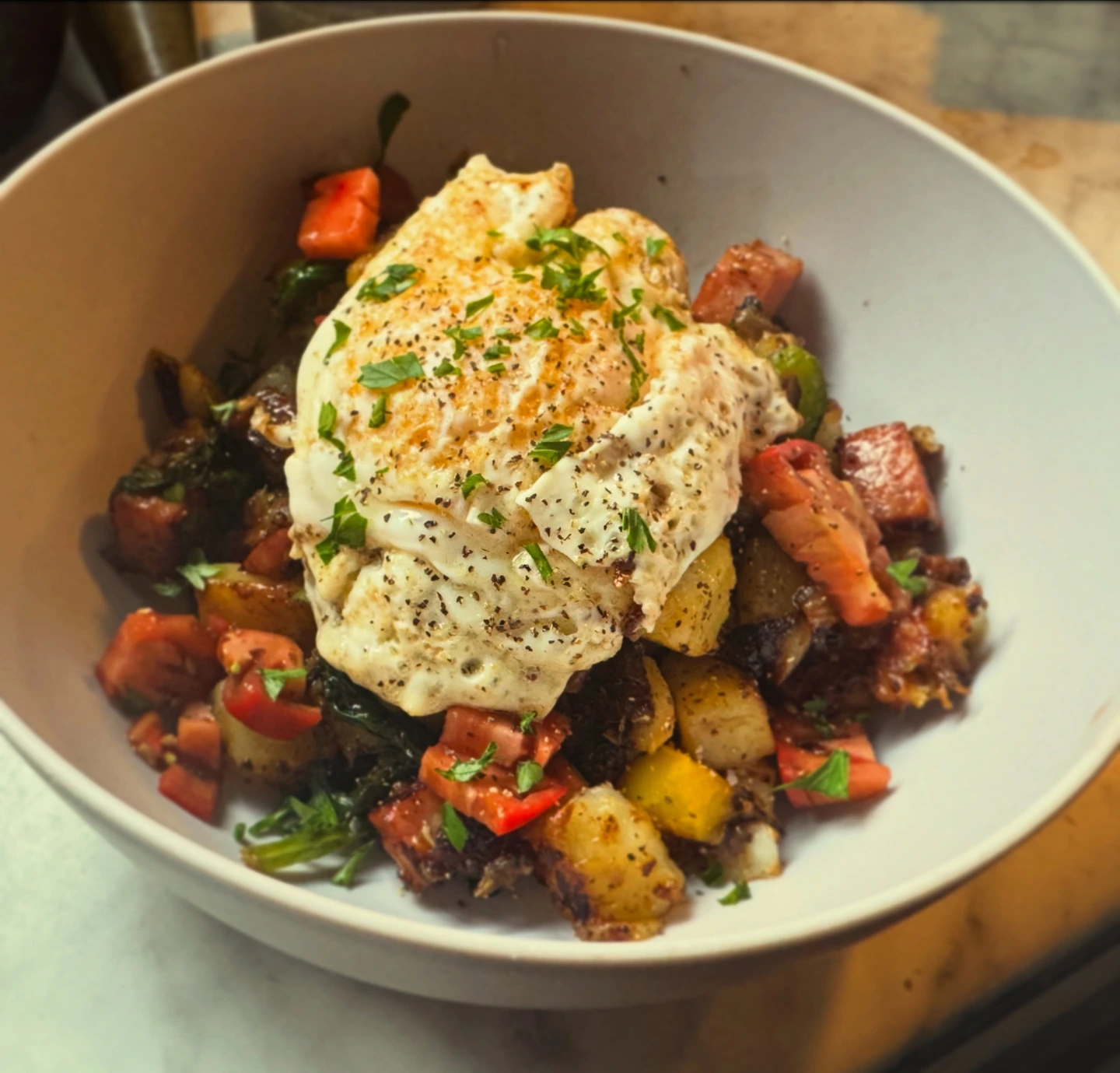 Fried egg served over browned potato and vegetable breakfast hash