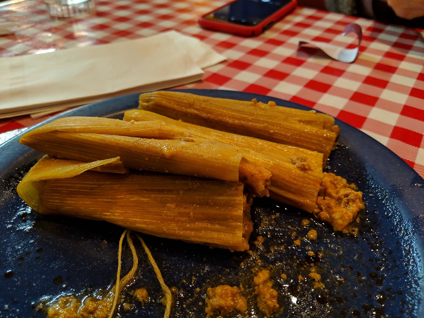 Corn-husk-wrapped tamales on a blue plate at Airport Grocery in Cleveland