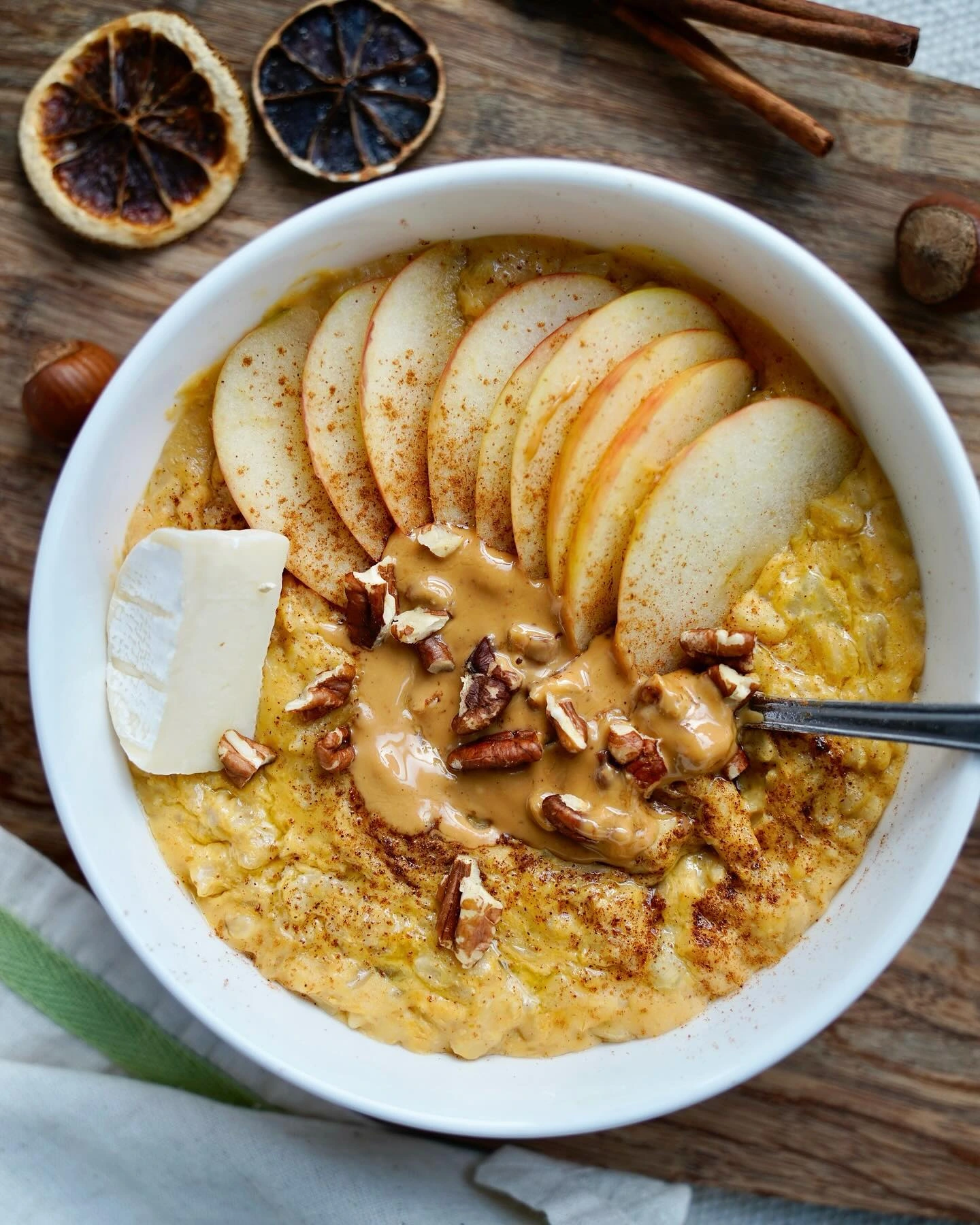 Apple cinnamon oatmeal topped with apple slices, nut butter and chopped nuts