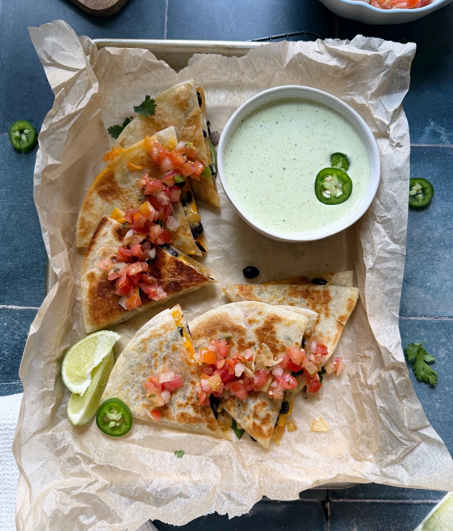 Black bean and cheese quesadilla wedges on a tray with salsa and dipping sauce