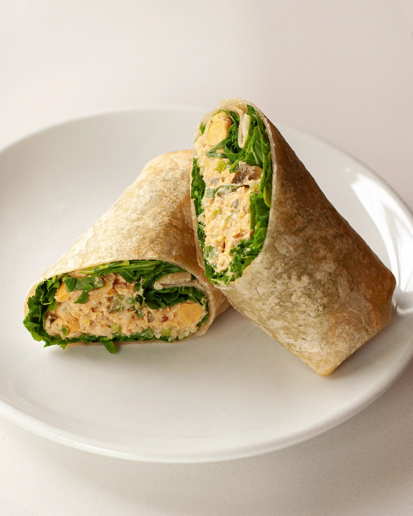 Chickpea salad wrap with leafy greens, cut into halves