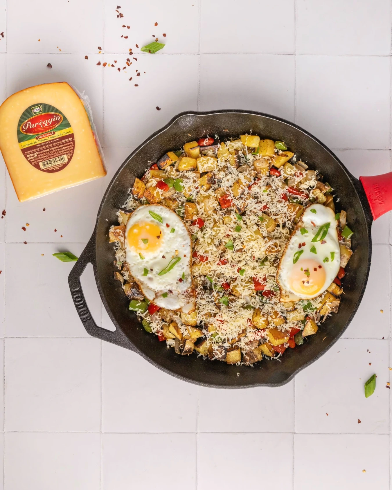 Potato and pepper breakfast hash topped with two fried eggs and grated cheese