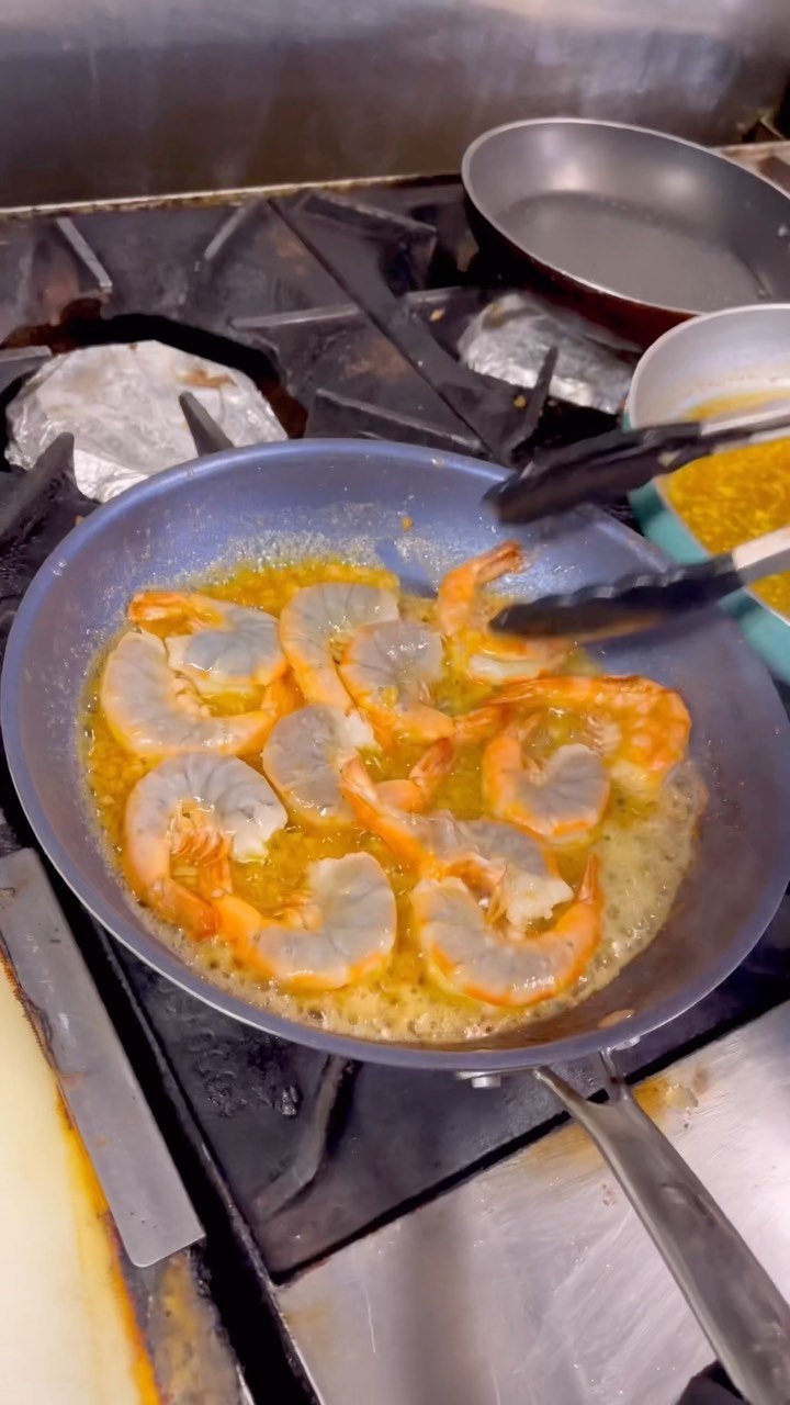 Garlic butter shrimp cooking in a skillet at Geste Shrimp Truck