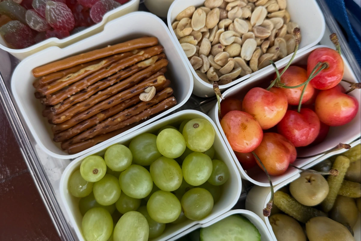 Packed road-trip snack box with cherries, grapes, cucumber, nuts, crackers and pretzels
