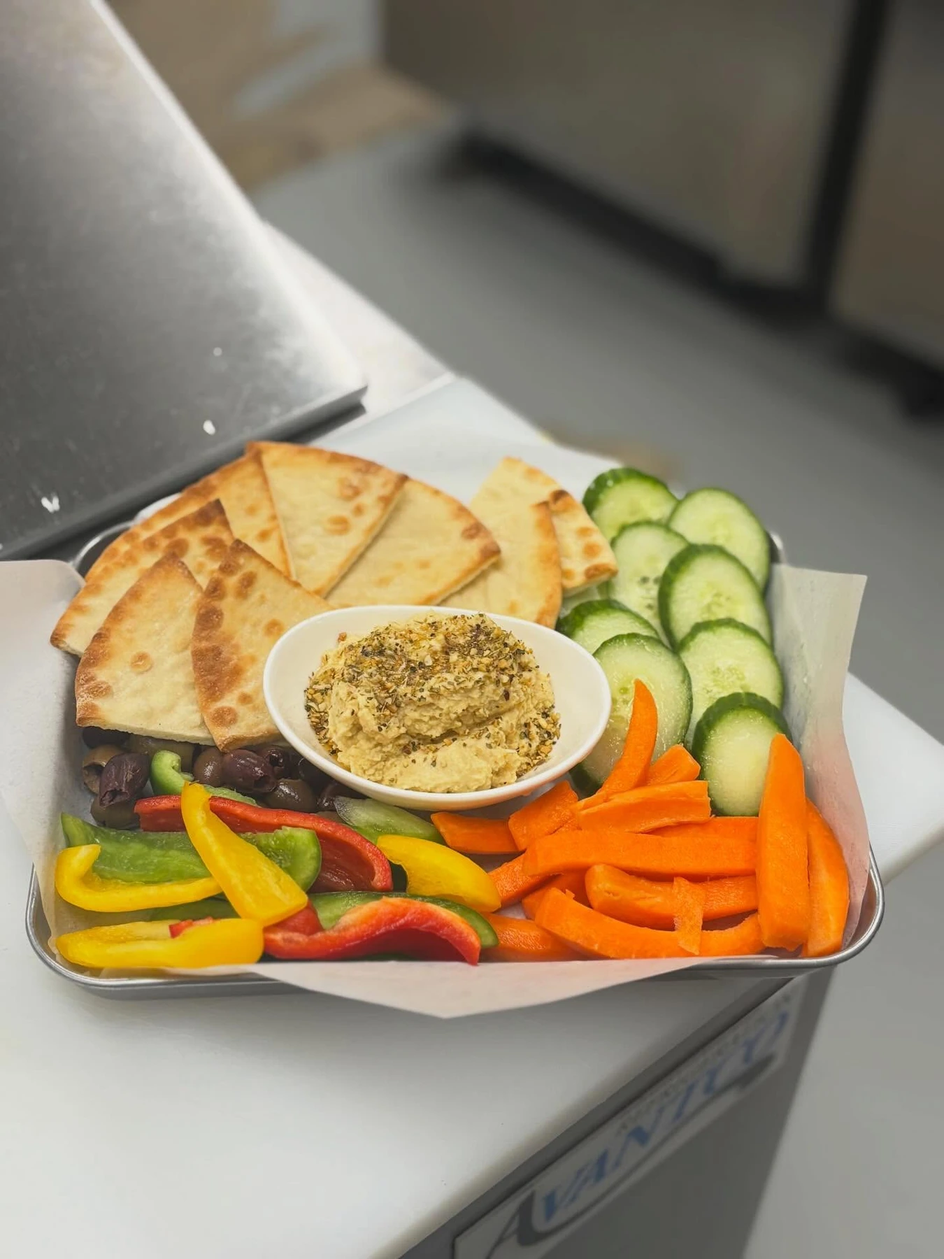 Hummus with colorful bell pepper strips, cucumbers, carrots and toasted bread