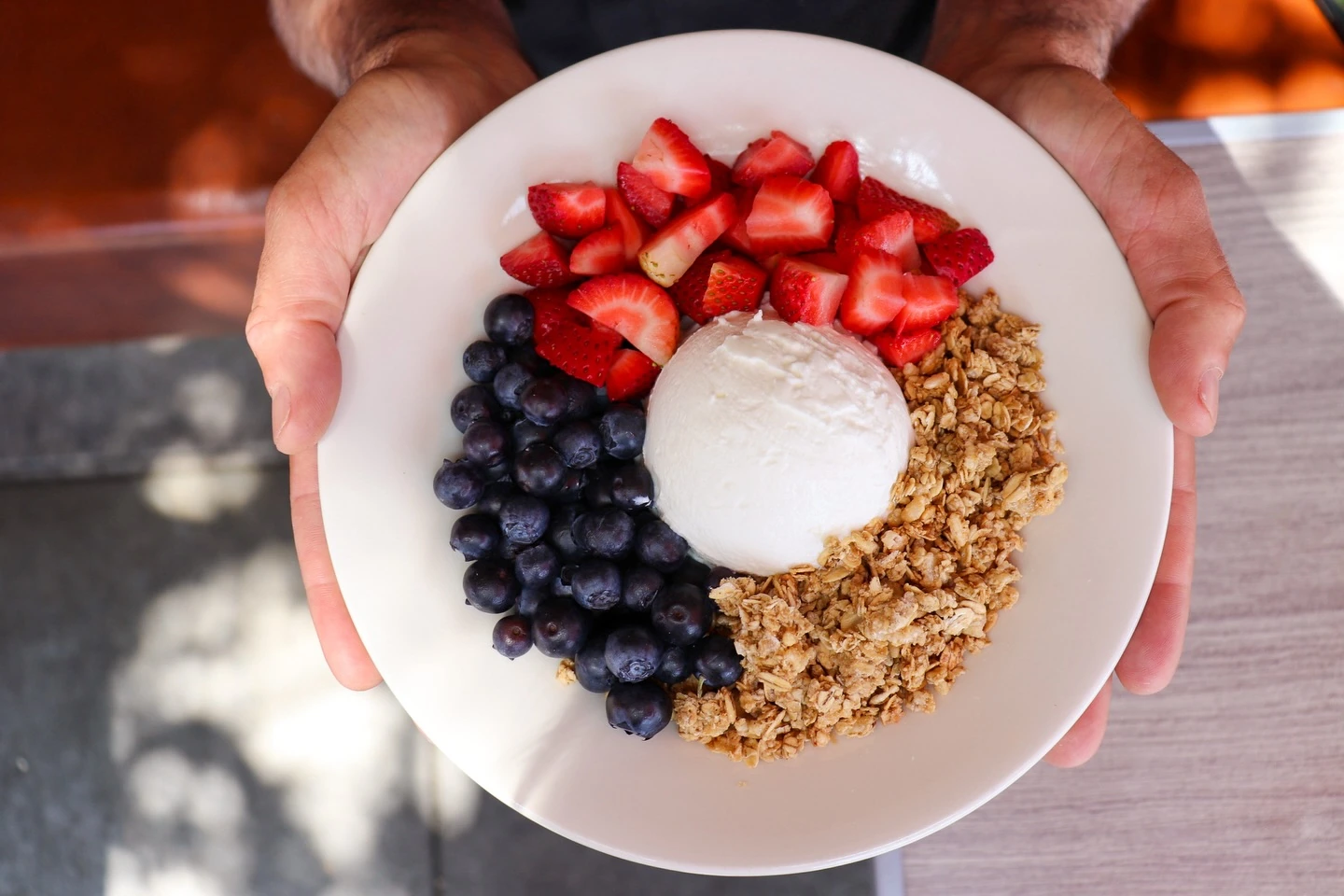 Greek yogurt served alongside strawberries, blueberries and granola