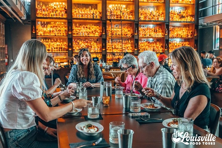 Guests sharing food and bourbon at a table on Louisville Food Tours’ NuLu walking dinner