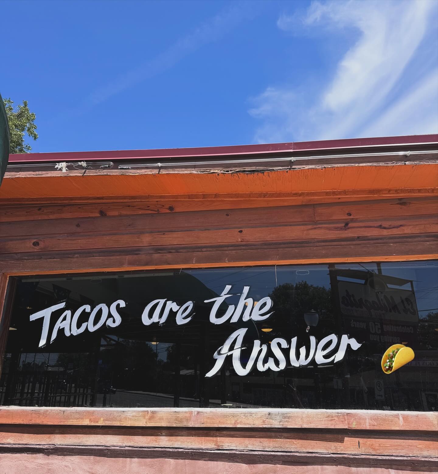 El Milagrito Cafe window with its Tacos are the Answer sign