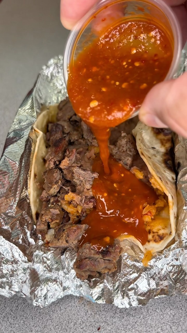 Salsa being poured over a Taco Palenque taco