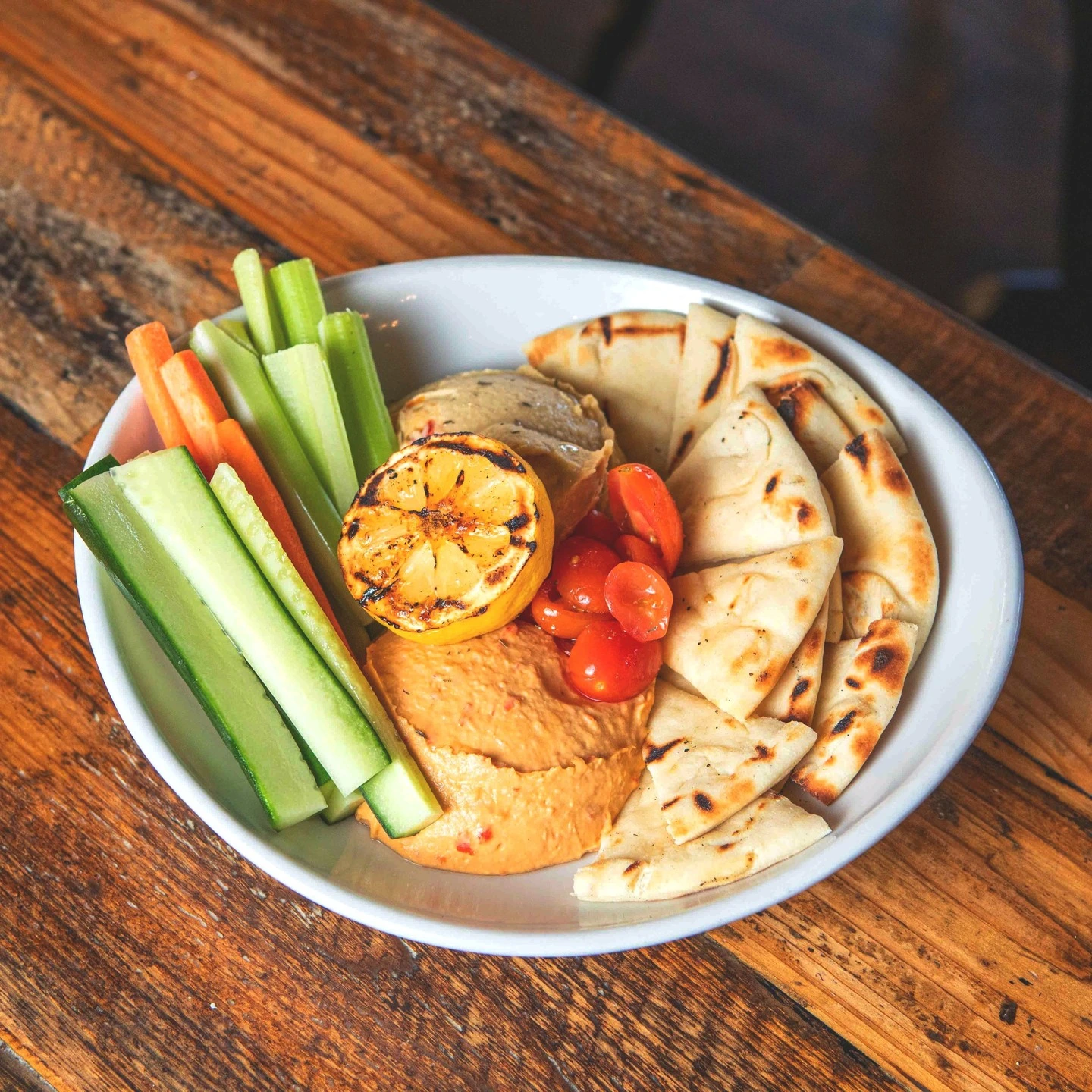 Hummus with cucumber, celery and carrot sticks, pita and grilled lemon