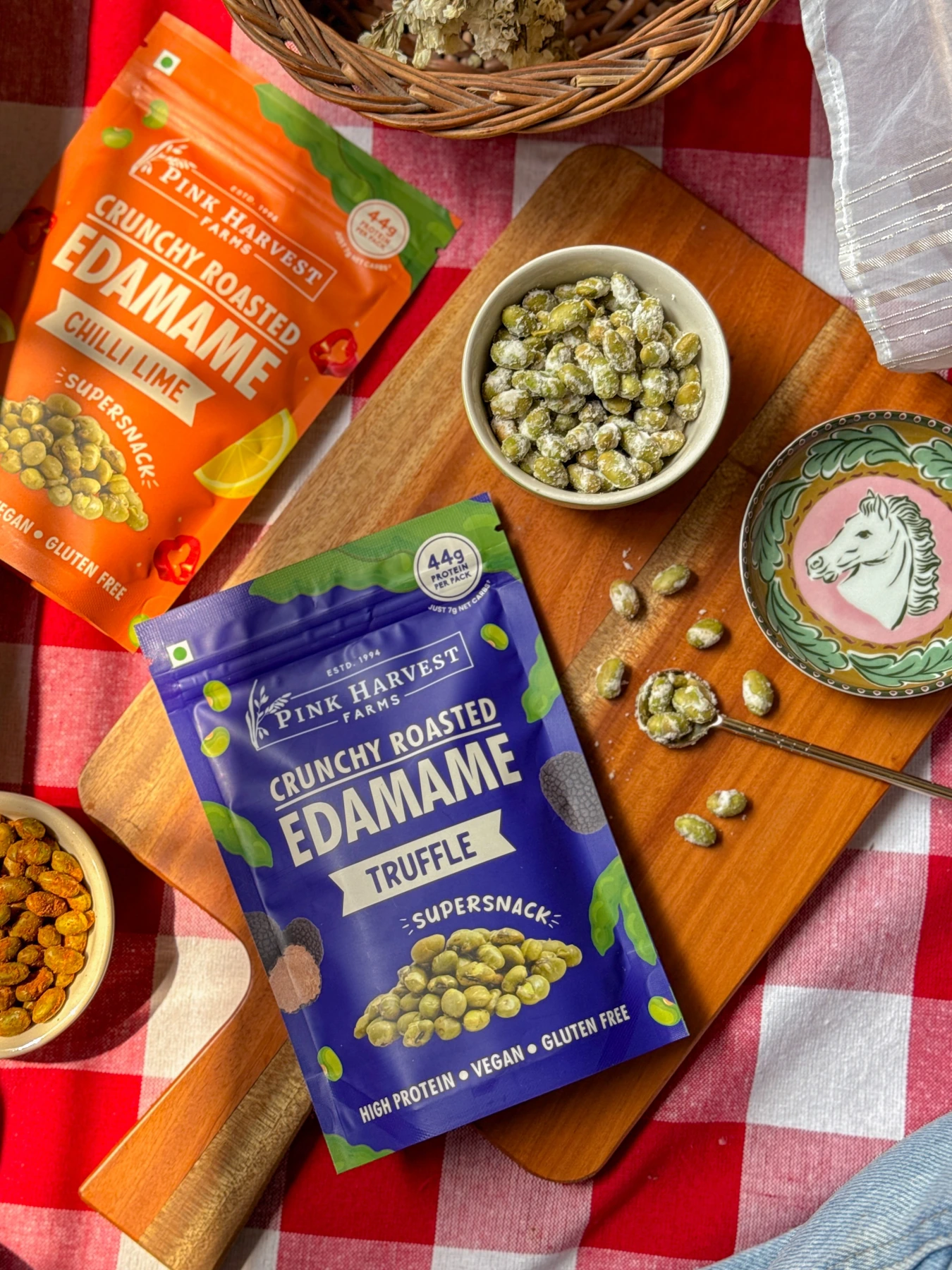 Roasted edamame snacks in bowls and resealable packs on a picnic cloth