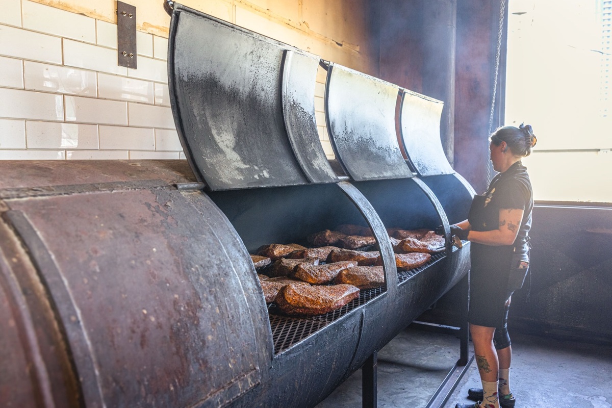 A pit worker tending smoked meat at Franklin Barbecue in Austin, Texas