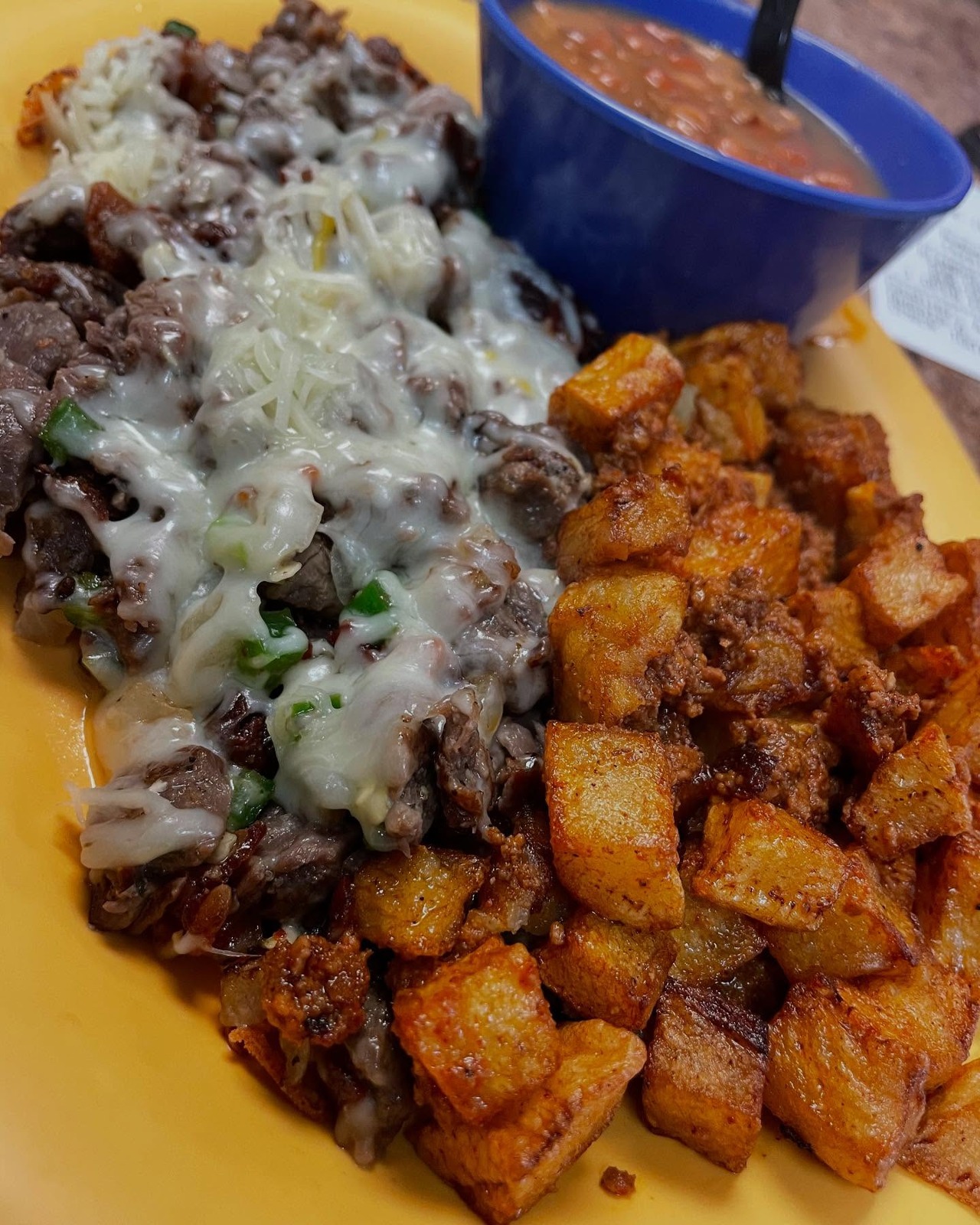 A meat and cheese plate with potatoes and beans at Tacos N’ Salsa