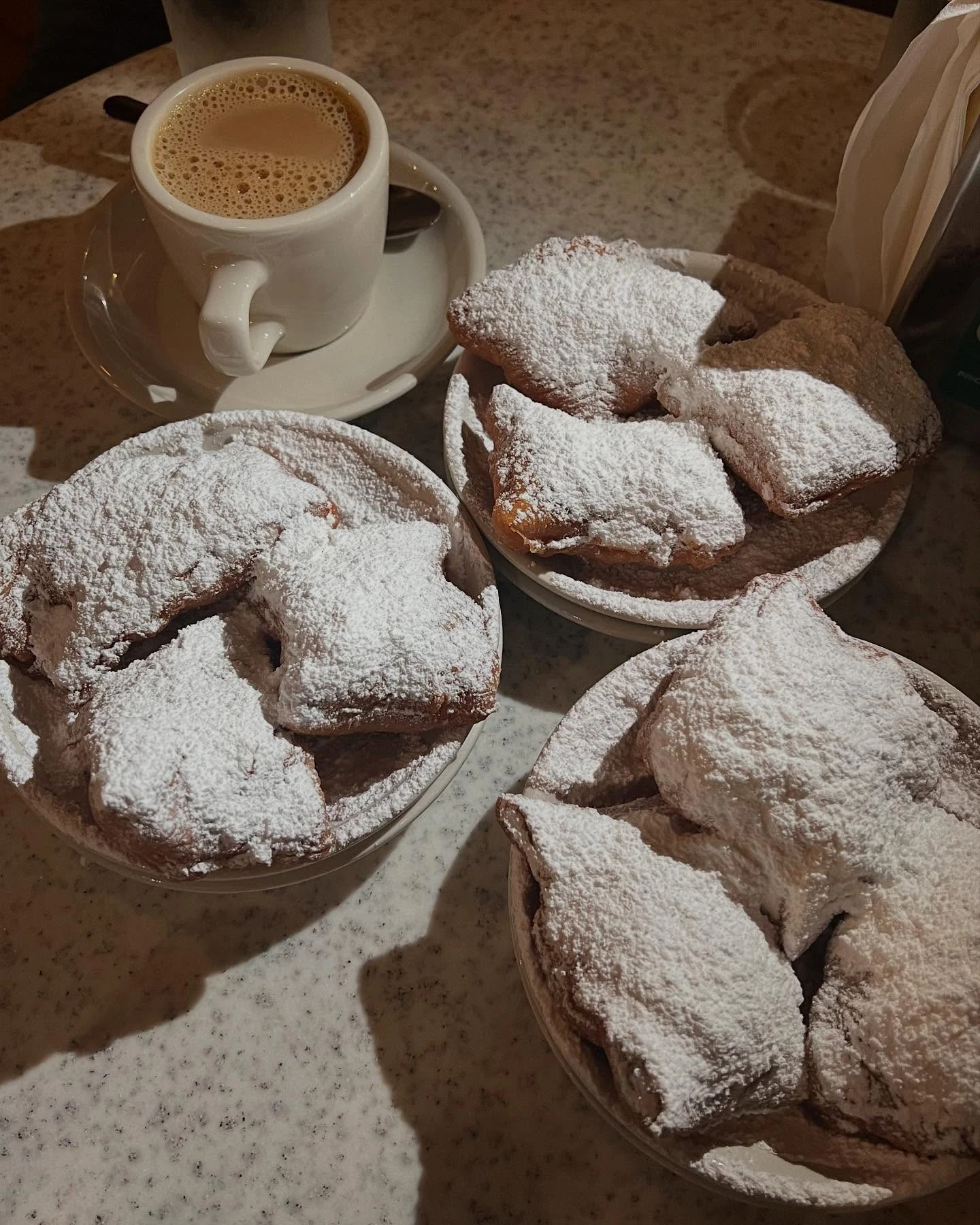 Plates of powdered-sugar beignets with café au lait at Café du Monde