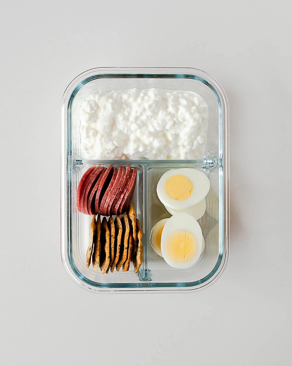 Snack box with hard-boiled eggs, crackers, salami and cottage cheese