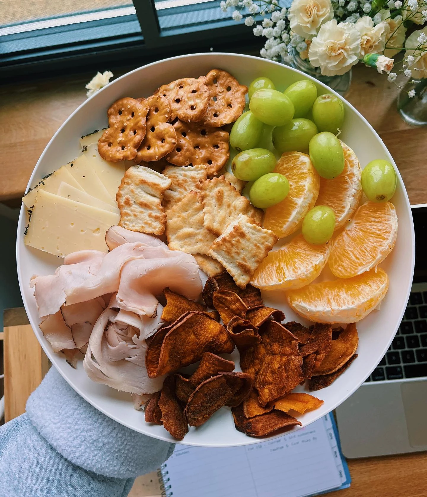 Snack plate with cheese slices, crackers, turkey, grapes and orange segments