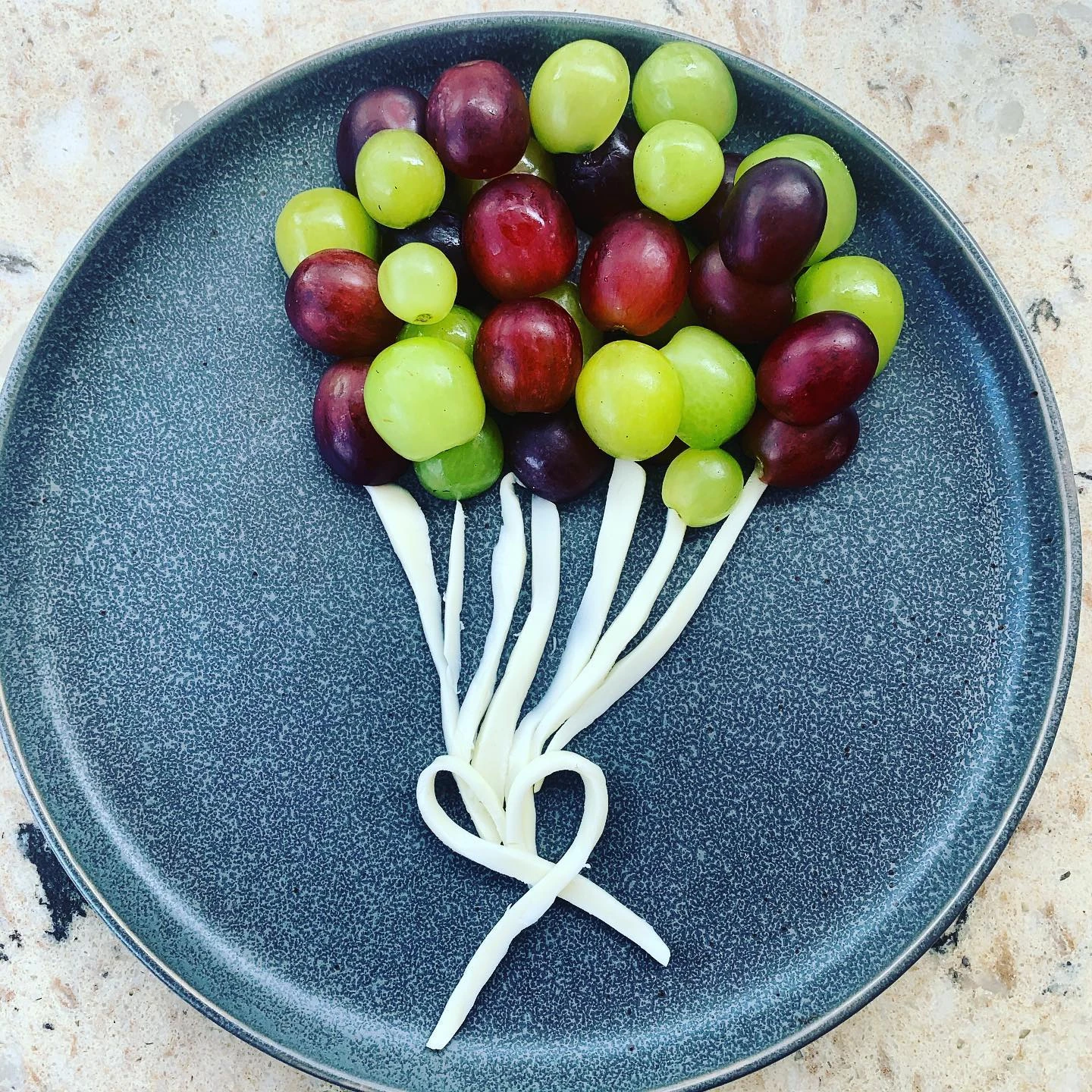 Grapes and strips of string cheese arranged on a plate