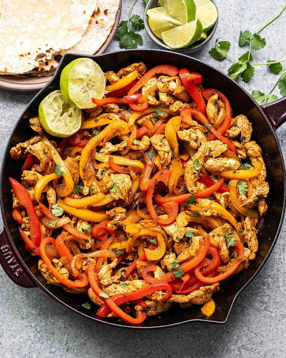 Chicken strips, bell peppers, and onions cooked in a skillet with lime
