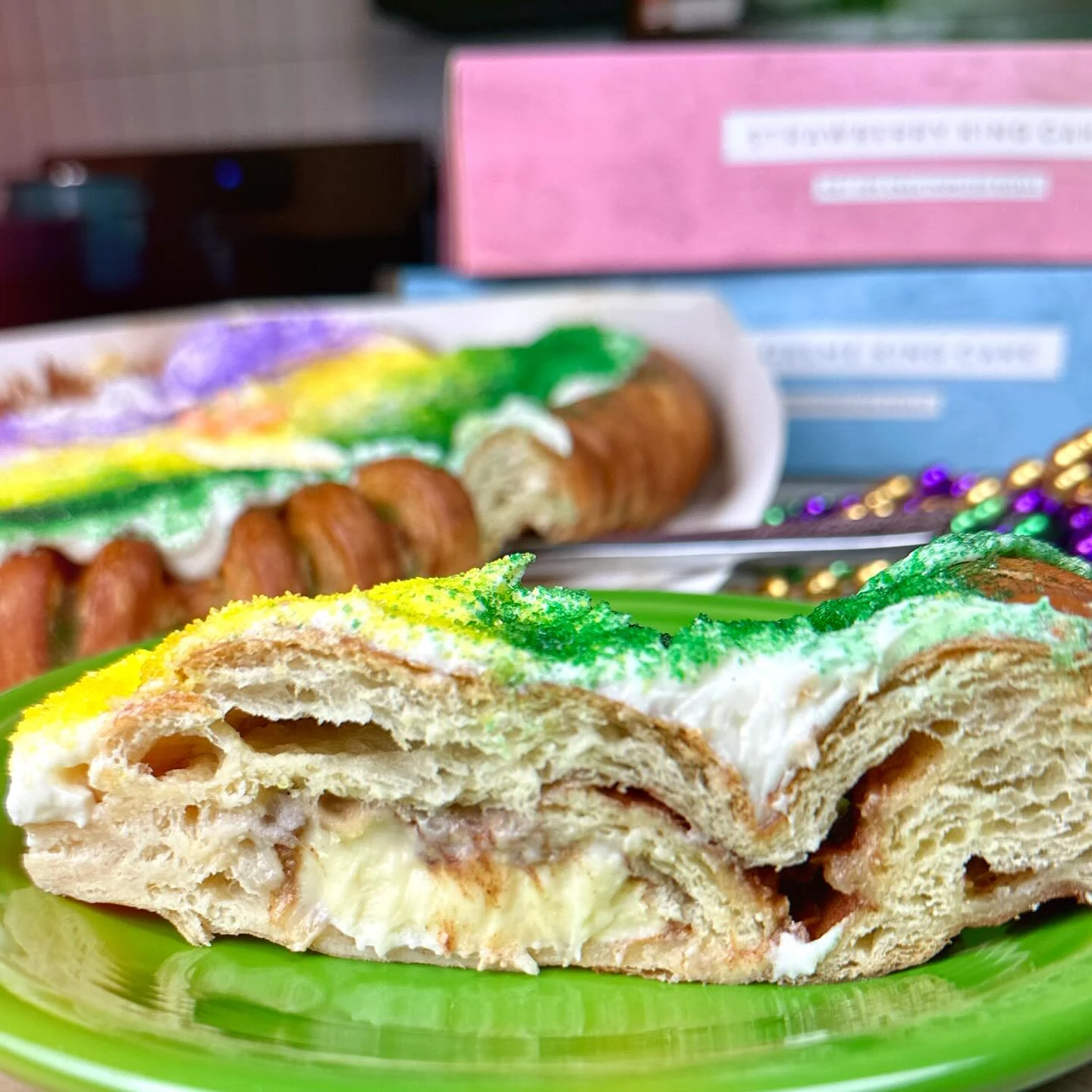 Slice of Dong Phuong cream-cheese king cake with purple, green, and gold sugar