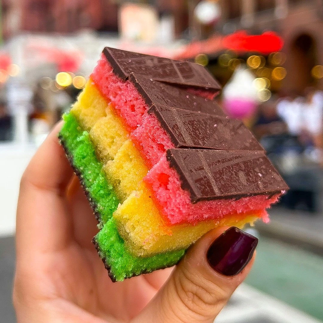 Chocolate-topped Italian rainbow cookies with red, yellow and green layers at Ferrara Bakery
