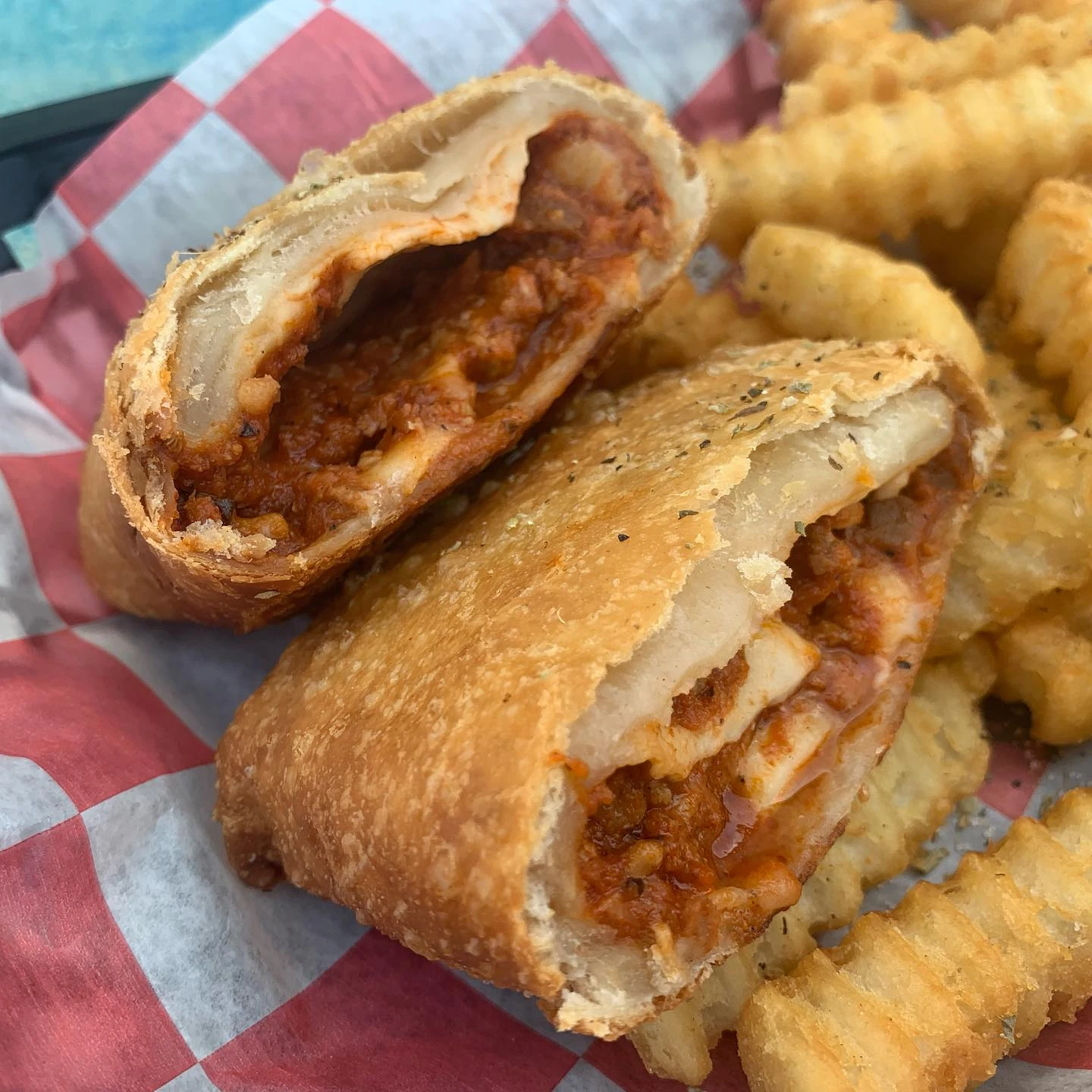 Crisp pizza puff cut open to show its tomato, cheese, and sausage filling