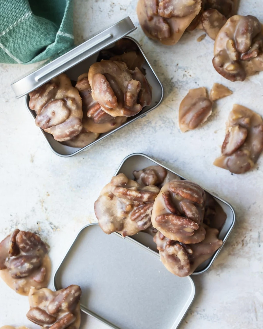 Pecan pralines arranged in small tins and on a tabletop