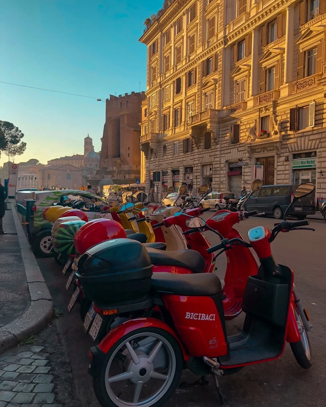 Colorful scooters parked along a sunlit street in Rome