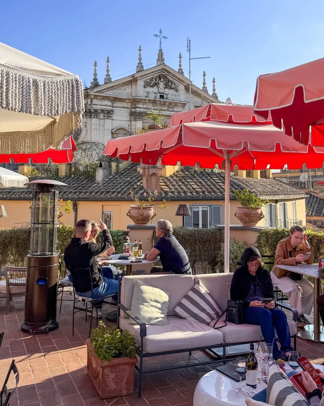 Outdoor café terrace with red umbrellas overlooking Rome