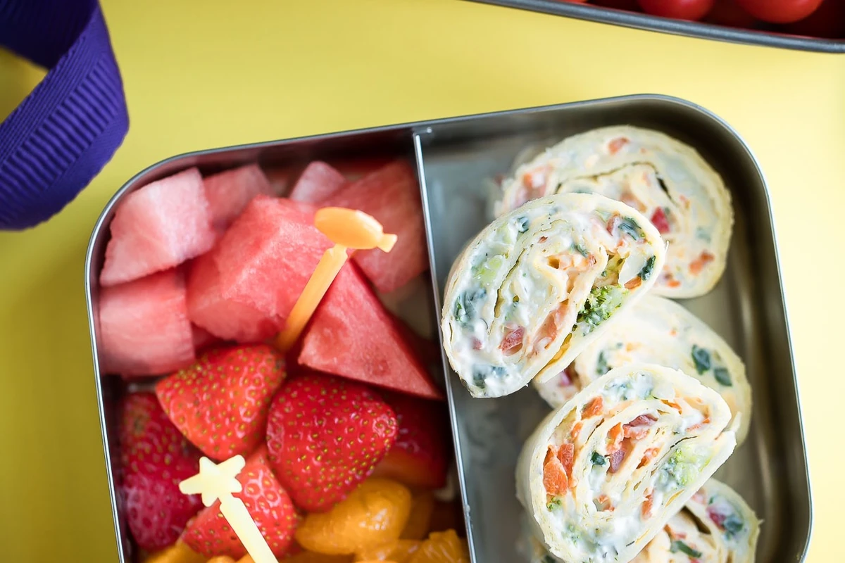 Packed snack boxes with vegetable pinwheels, fresh fruit, tomatoes and crackers