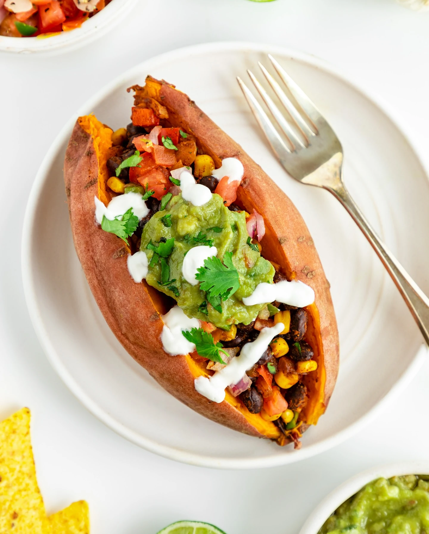Baked sweet potato filled with black beans, corn, avocado and tomato salsa