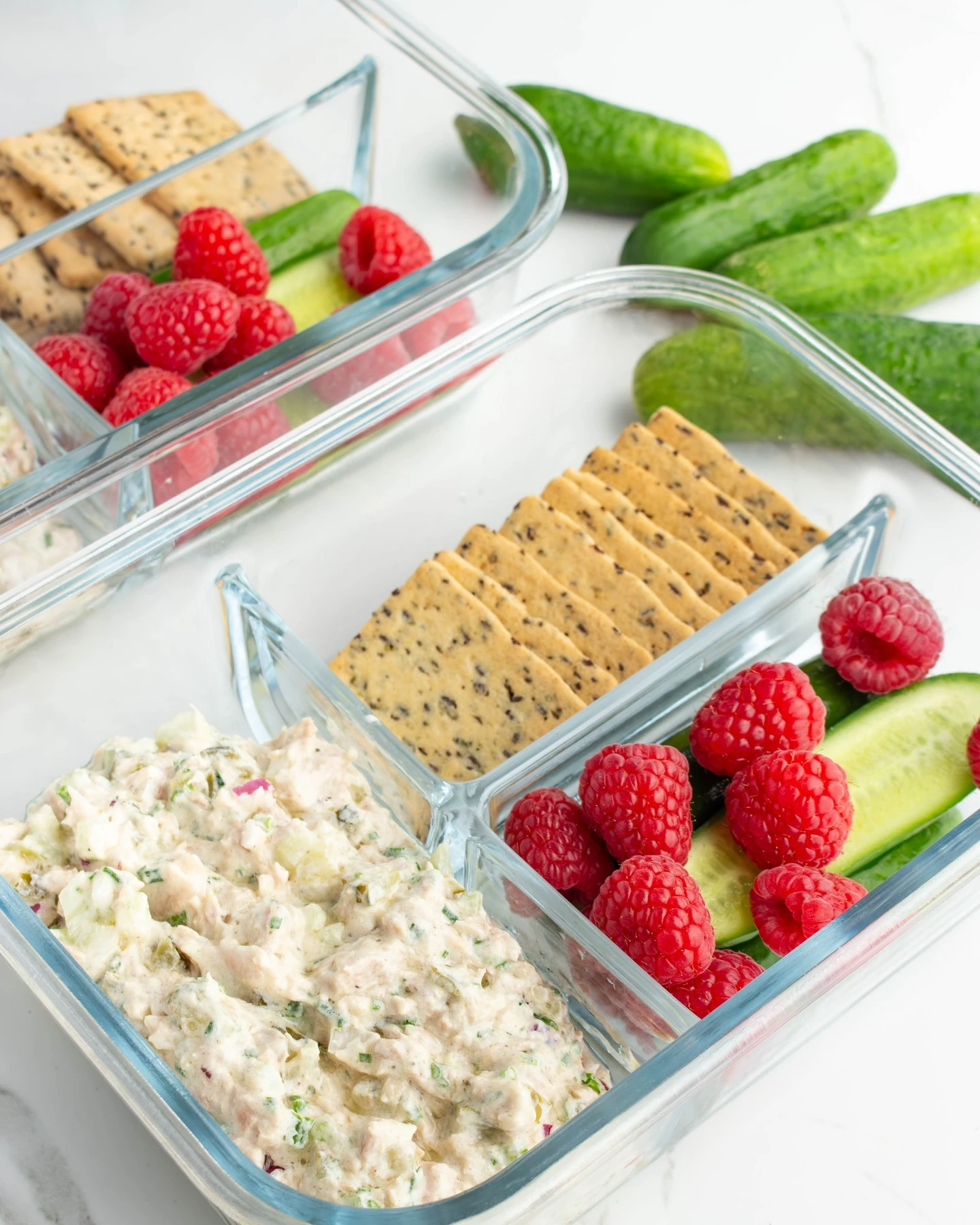 Tuna salad lunchbox with crackers, cucumber and raspberries