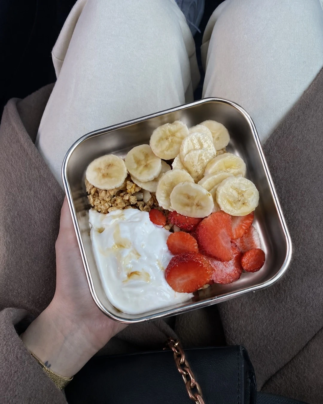 Yogurt, granola, strawberries and banana arranged in a travel snack box