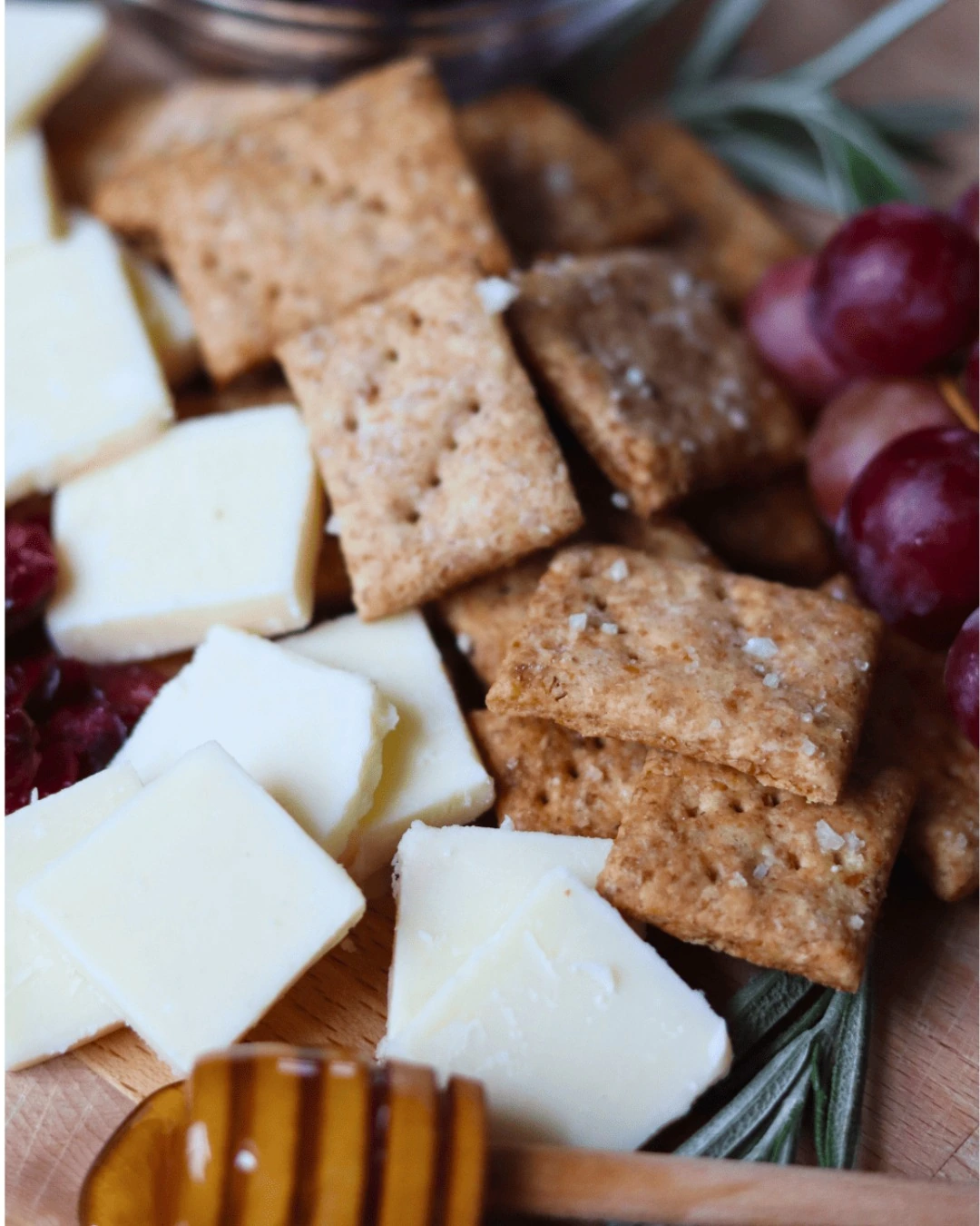 Sourdough whole-wheat crackers with cheese and grapes on a snack board