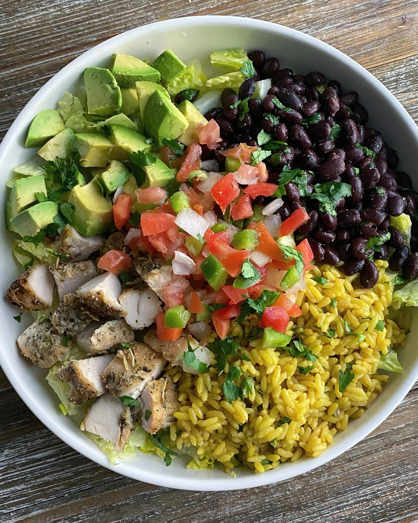 Balanced meal bowl with chicken, rice, black beans, avocado and tomato salsa