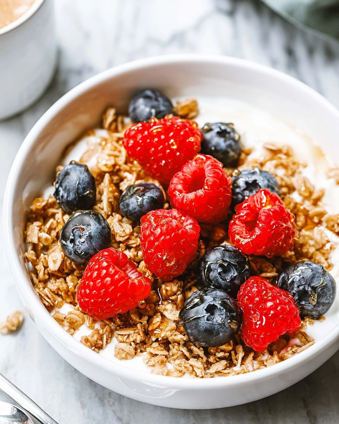Yogurt bowl topped with granola, blueberries, and raspberries